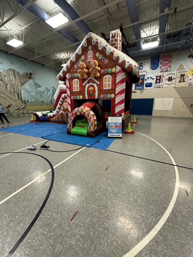A massive, colorful inflatable gingerbread house combo featuring candy cane pillars, frosting-style roof peaks, and festive holiday decorations for event rentals.