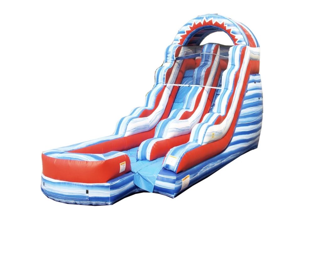 A 15-foot tall patriotic inflatable slide named "Freedom Falls," featuring red, white, and blue colors with a single climbing lane and a steep sliding lane, set up as a water slide in a Columbus, Ohio backyard.